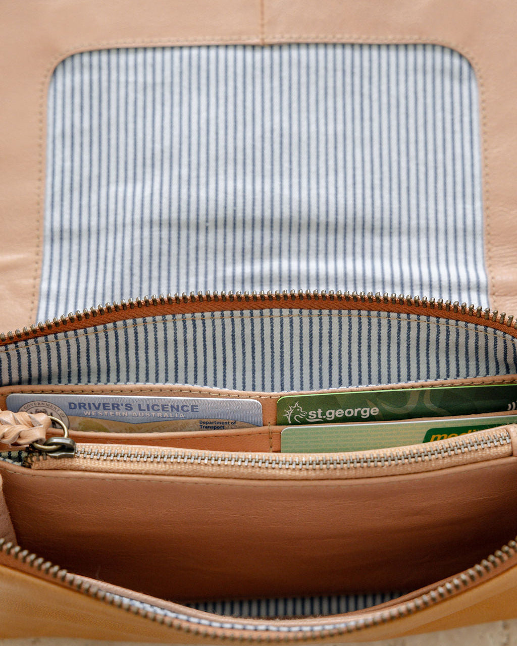 Open leather wallet with striped lining and various cards inside