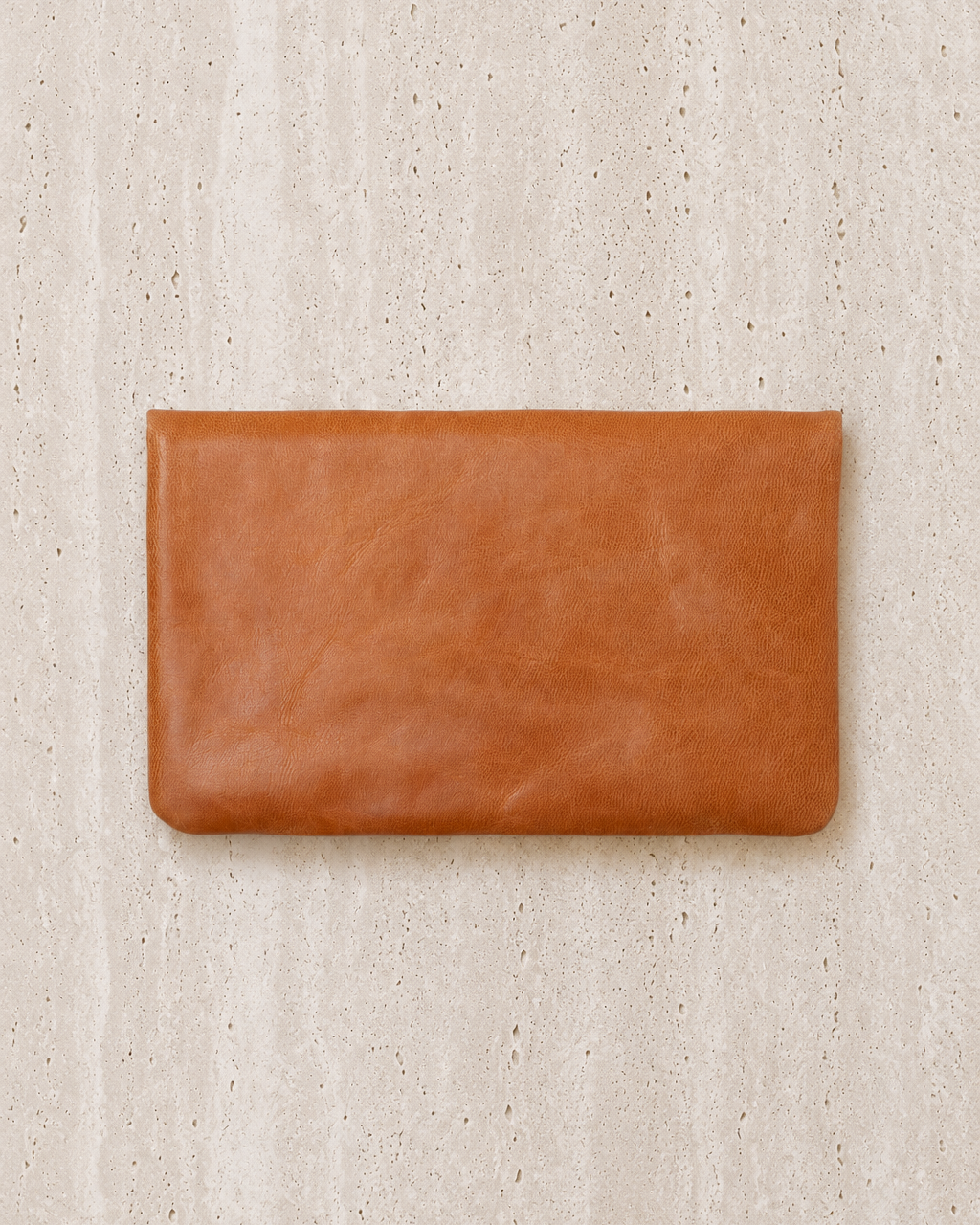 Brown leather clutch on a beige textured background