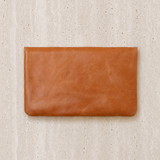 Brown leather clutch on a beige textured background