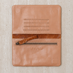 Ovae Tan leather wallet with zipper on a textured beige background