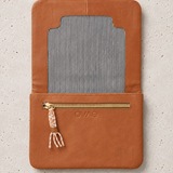 A tan leather wallet or organizer cover with a striped fabric insert and a gold zipper pocket, shown flat on a light textured background. The brand name 'OWS' is embossed on the front.